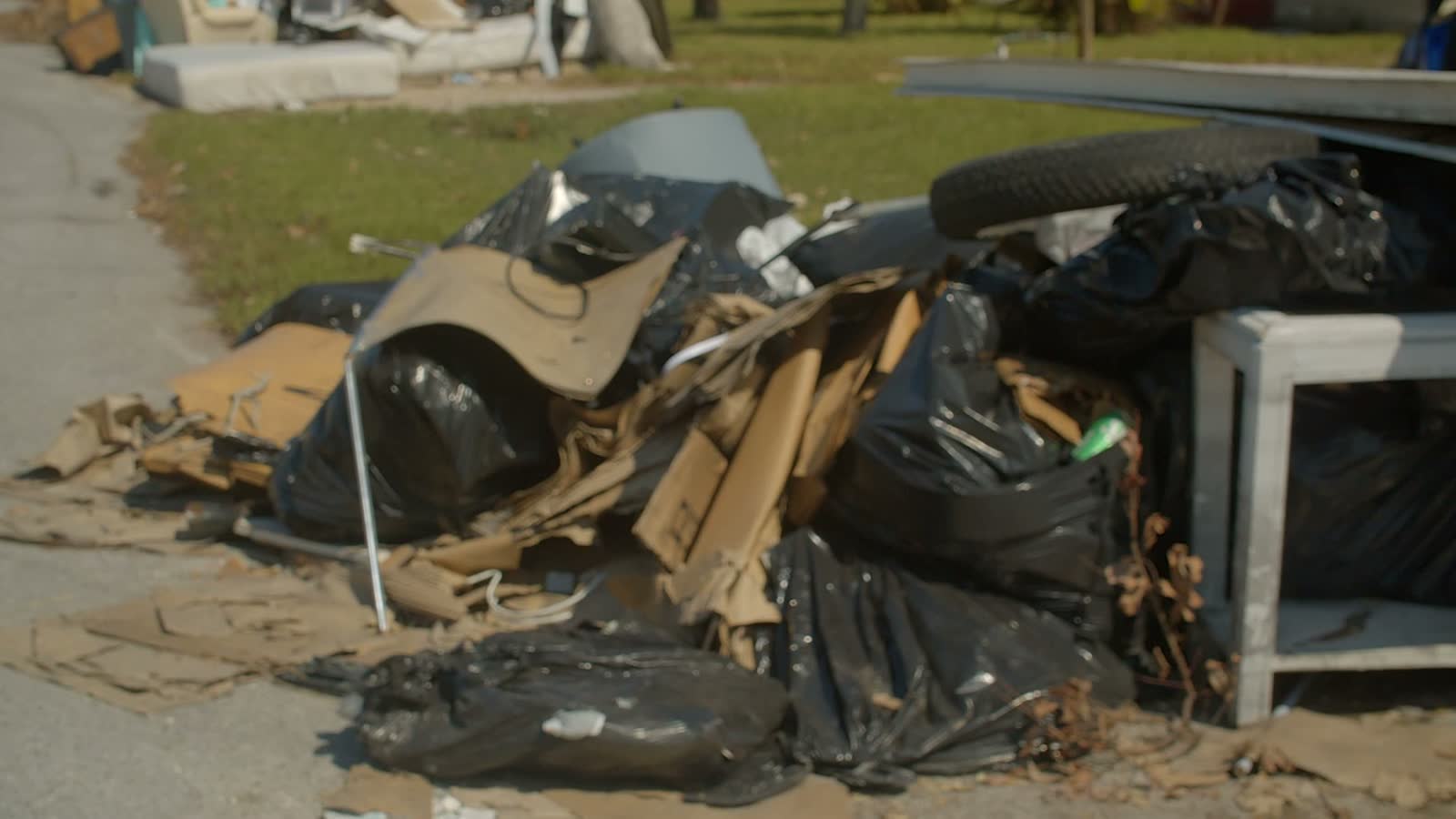 Storm wreckage and structural debris piled at the curb for removal