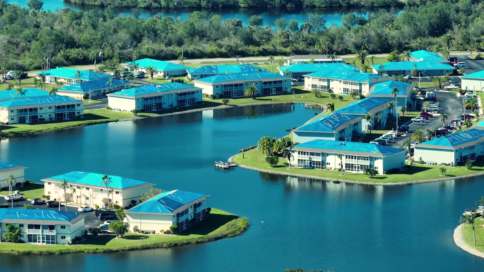 Aerial of a waterfront condominium community with blue tarps over hurricane-damaged roofs