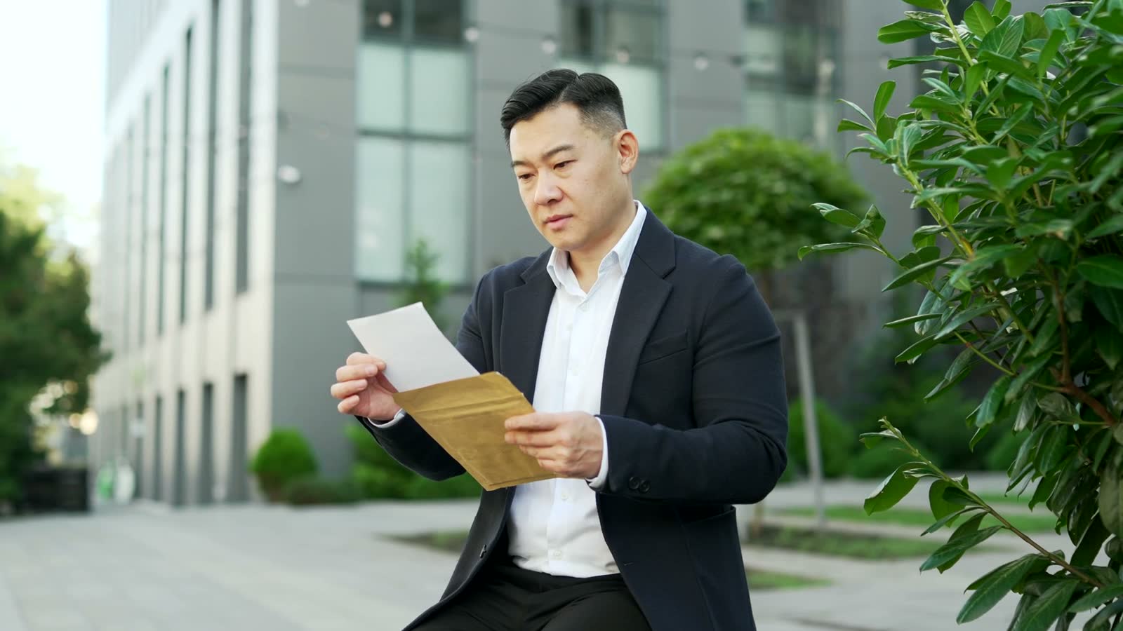 man-reads-letter-outside-office-building-looks-di.mp4