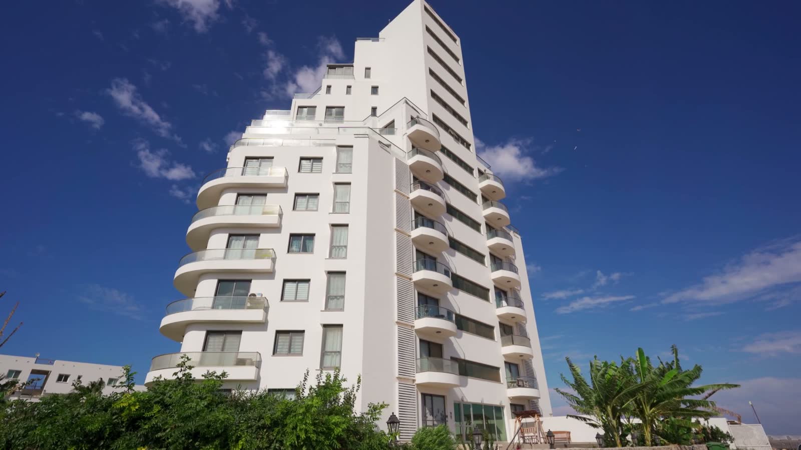 modern-white-apartment-building-against-bright-blu.mp4