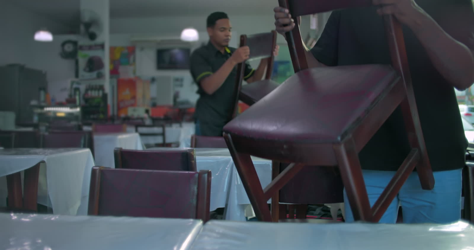 restaurant-workers-putting-chairs-on-top-of-tables.mp4
