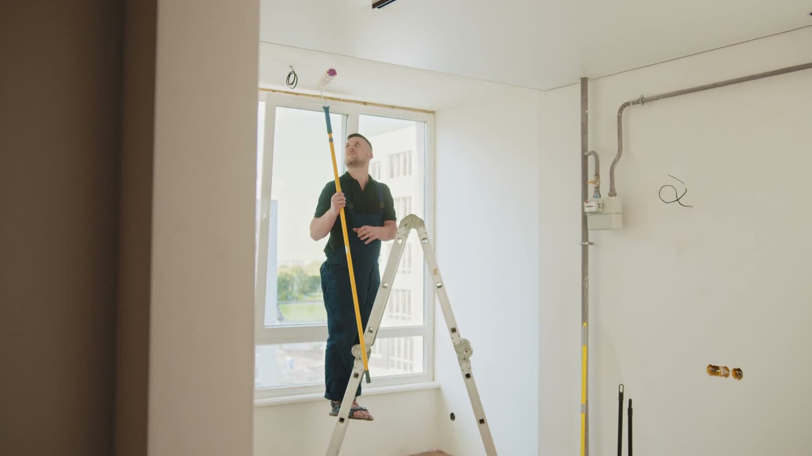 man-painting-ceiling-with-roller-on-ladder.mp4