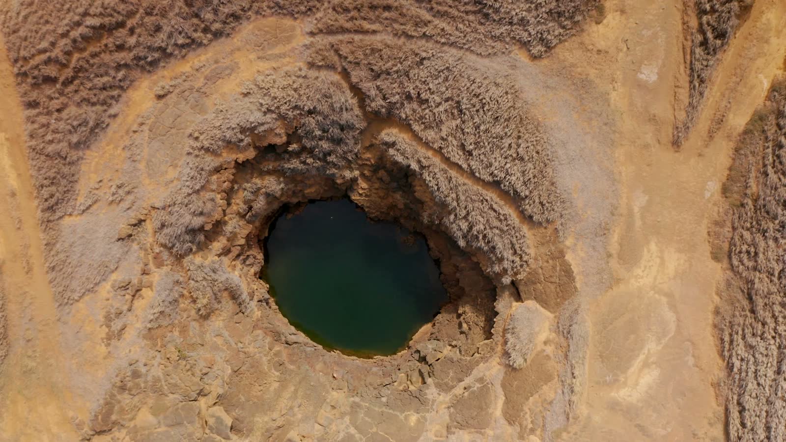water-filled-sinkhole-in-arid-terrain-top-down-v.mp4