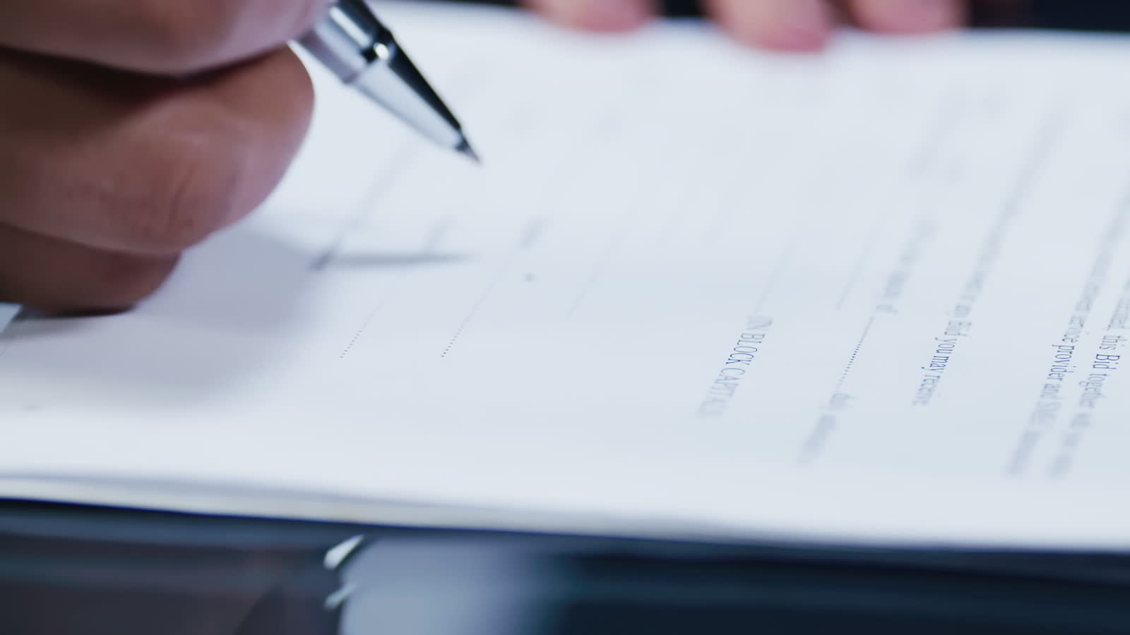 Close-up of a hand signing claim paperwork at a desk