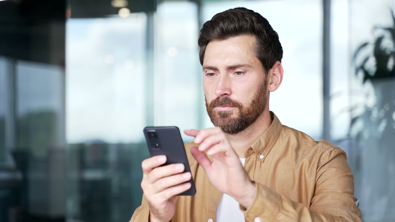 concerned-man-holding-phone-in-modern-workplace.mp4