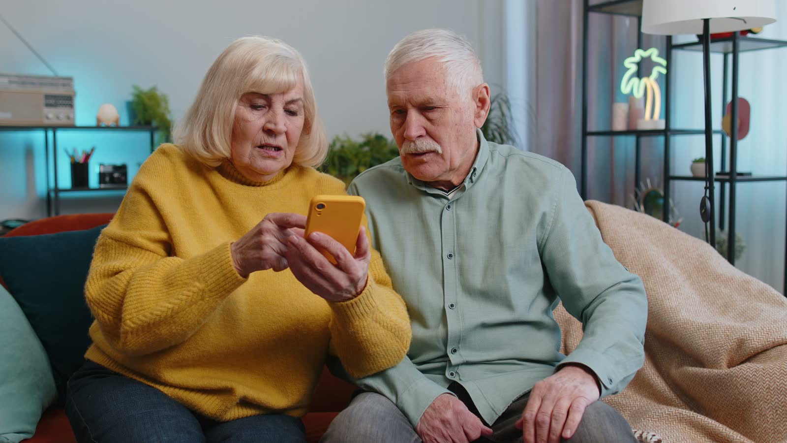 confused-seniors-using-a-mobile-phone-on-couch.mp4