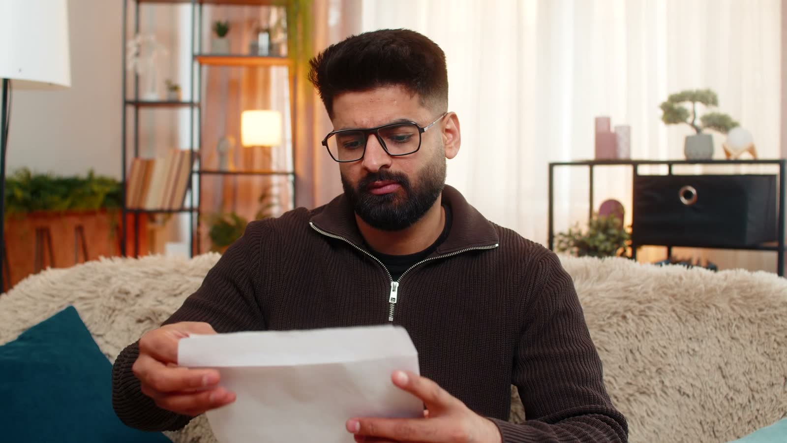 man-reading-letter-with-negative-reaction-on-sofa.mp4