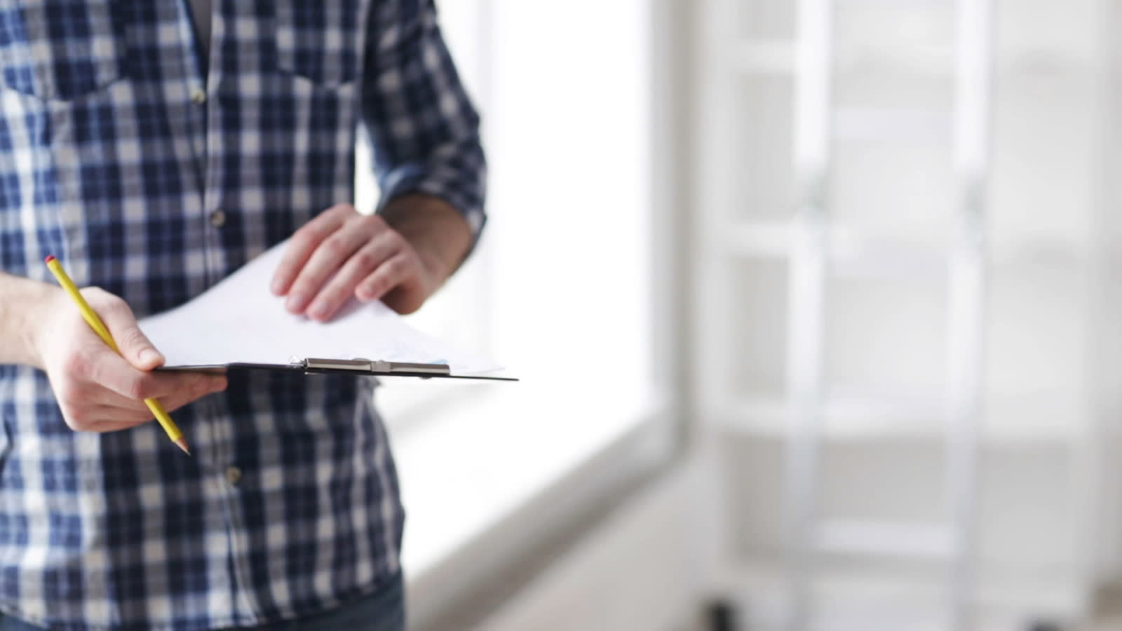 man-reviews-paperwork-on-clipboard-in-bright-room.mp4