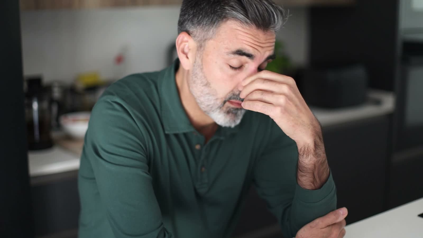 troubled-man-with-headache-sits-in-modern-kitchen.mp4