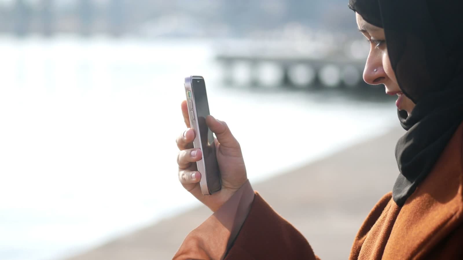 woman-with-headscarf-uses-cell-phone-near-water.mp4