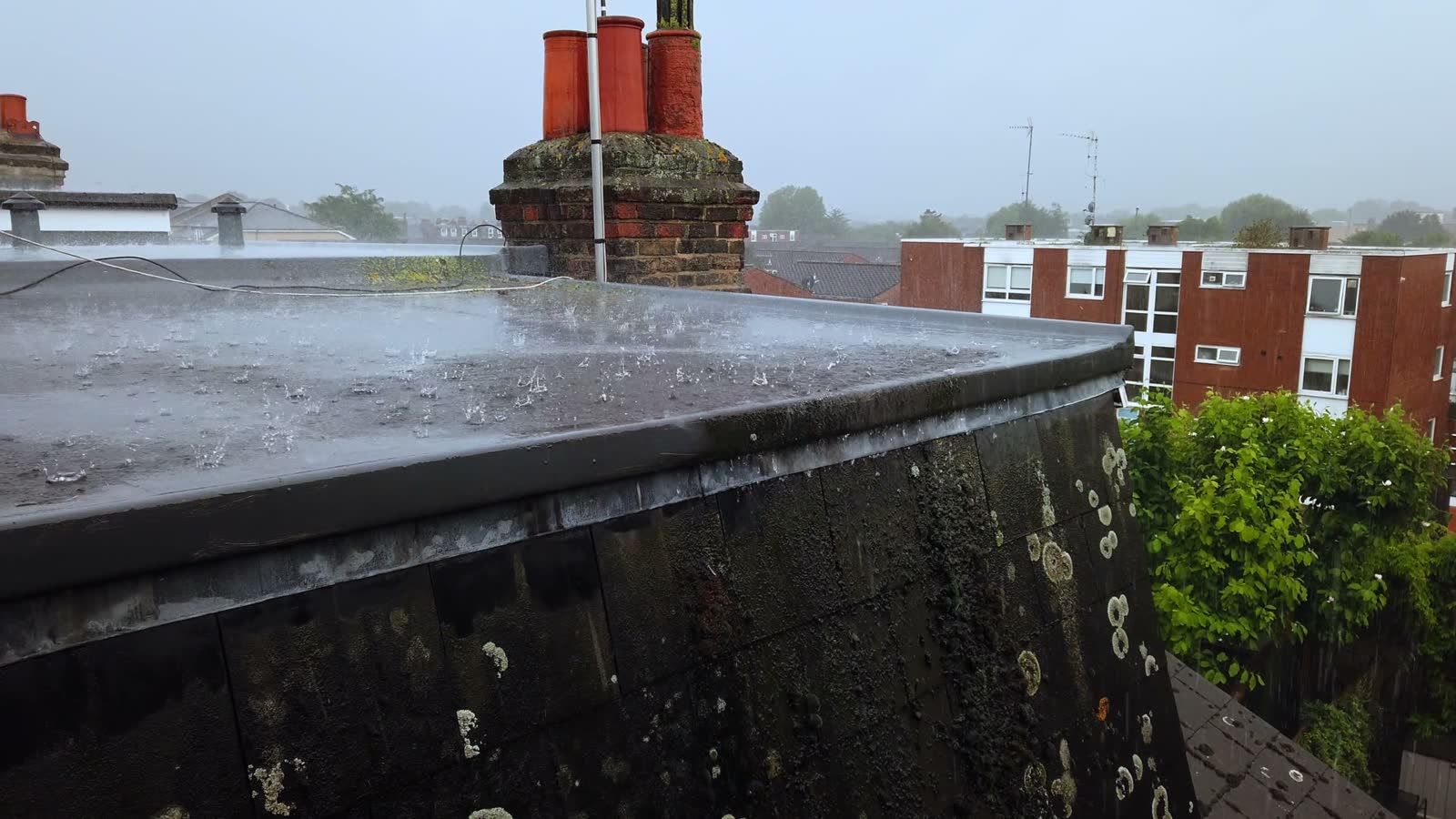 rain-pounding-flat-roof-in-suburban-setting.mp4