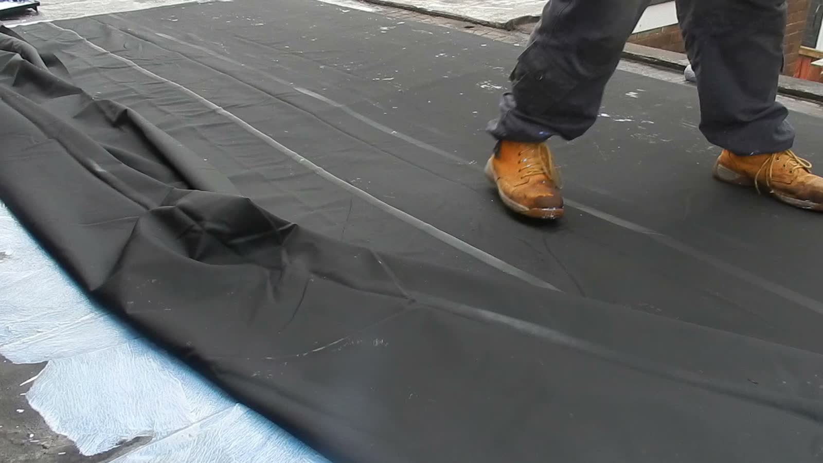 roofer-applying-black-sealant-with-a-push-broom.mp4