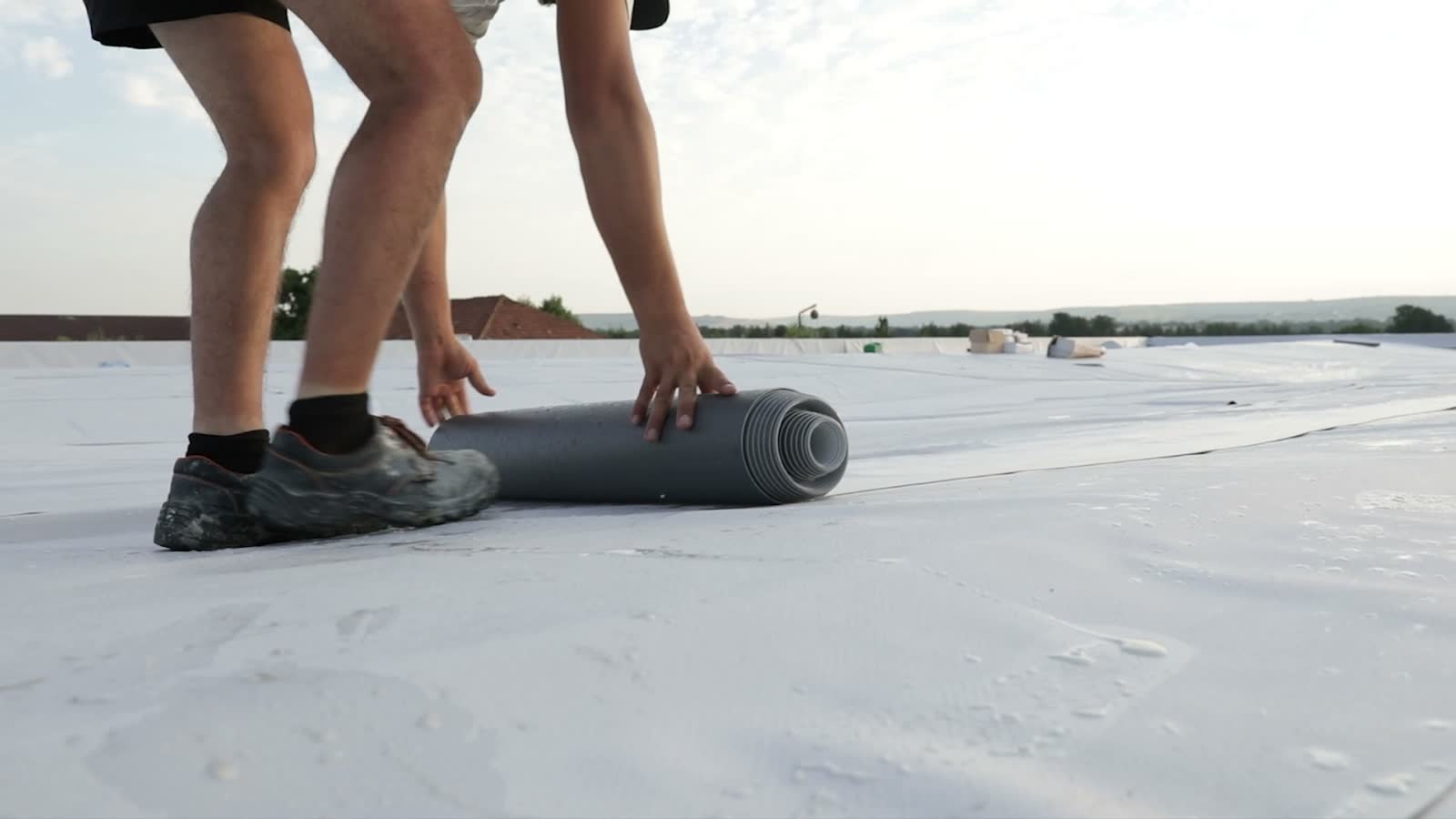 roofer-unrolls-material-on-a-white-rooftop.mp4