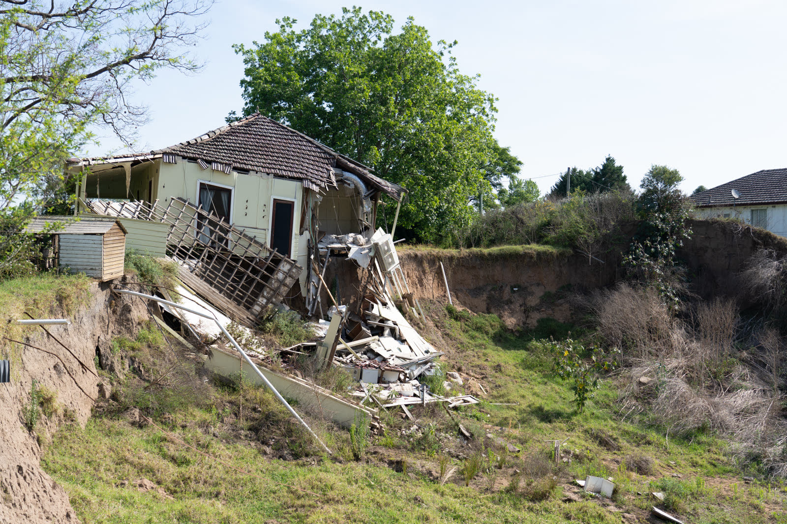 A house structurally collapsed and sliding into rubble at a cliff edge after storm erosion