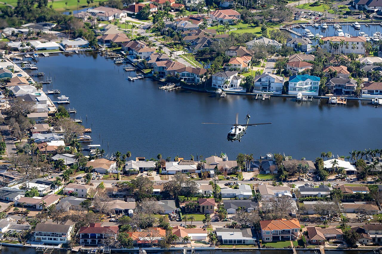 Aerial view of St. Petersburg-area canal neighborhoods during the October 13 presidential damage survey — debris piles line the streets